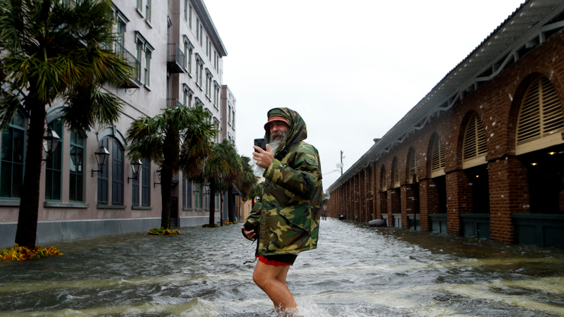 Local tour guide Larry Gerald live streams himself on social media as he crosses flooded S. Market Street at East Bay St. in the wake of Hurricane Matthew on October 8, 2016 in Charleston, South Carolina. Across the Southeast, Over 1.4 million people have lost power due to Hurricane Matthew which has been downgraded to a category 1 hurricane on Saturday morning. (Image: Getty)